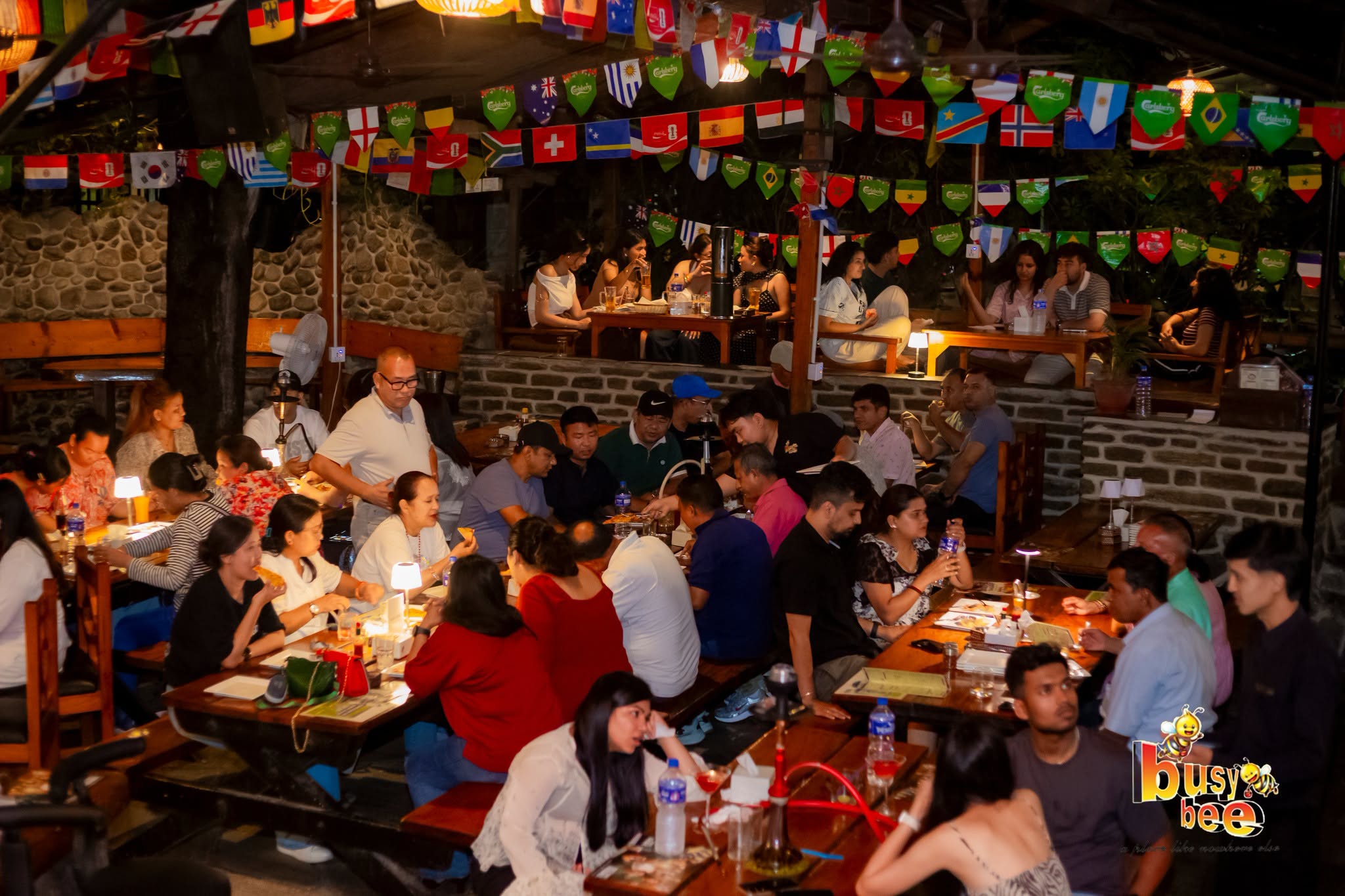 Full courtyard tables under string lights at dusk